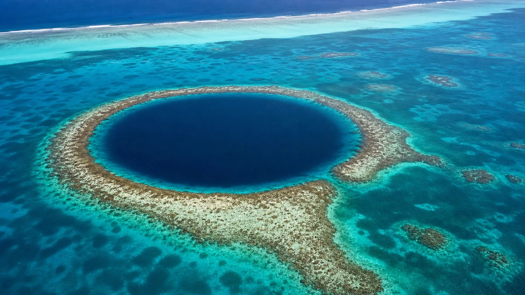 浅いカリブ海のサンゴ礁に開く円形のグレート・ブルー・ホール