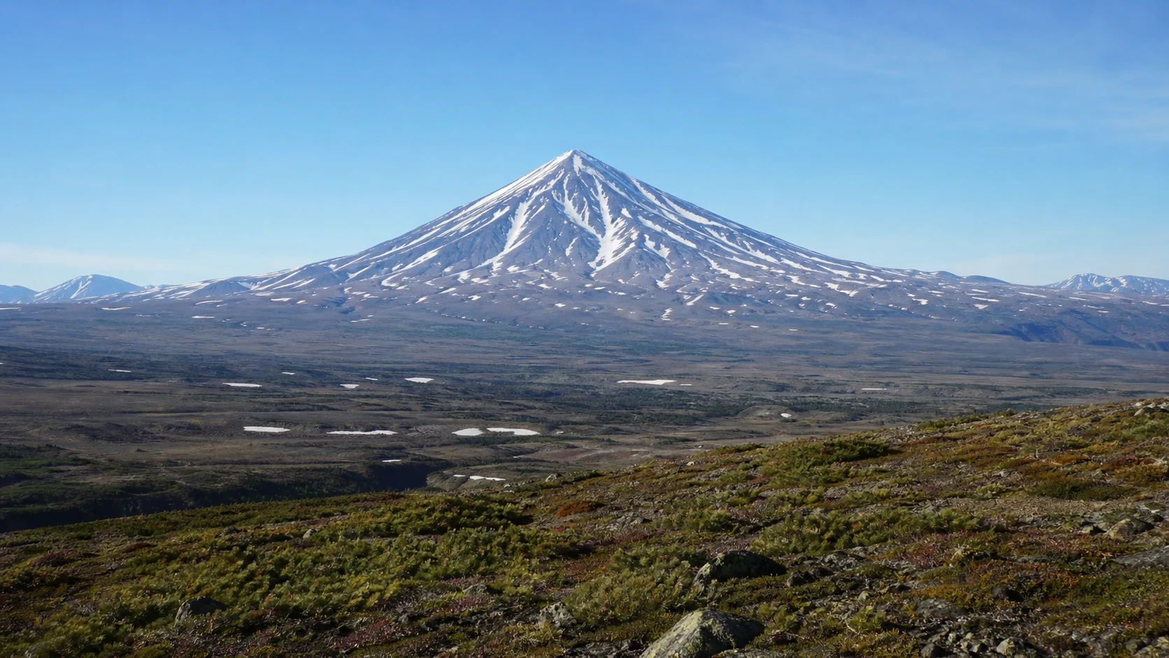 雪を頂く円錐形のオパラ火山とカムチャツカの原生景観